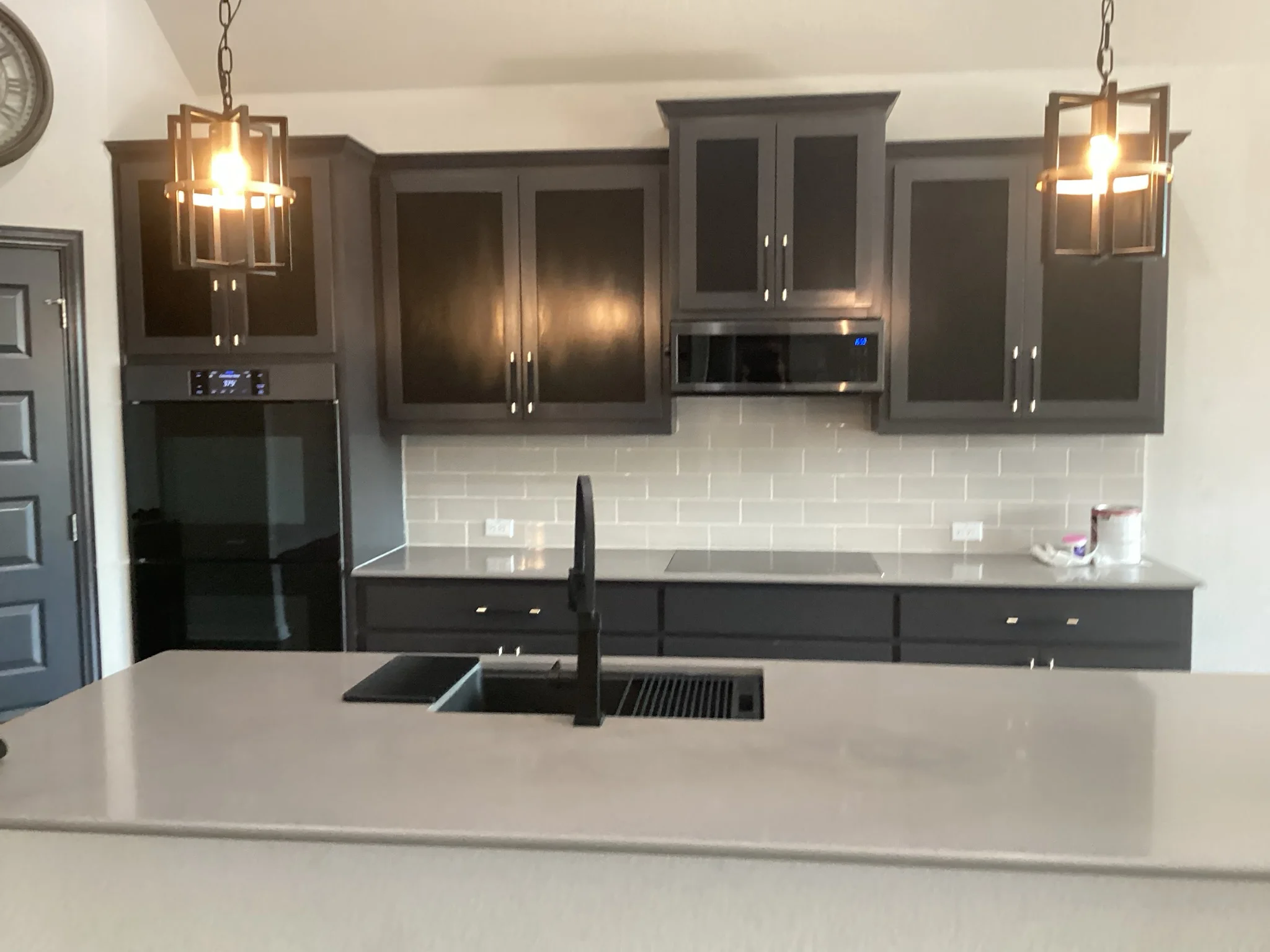 Charcoal gray painted kitchen cabinets with white subway tile backsplash and gray quartz countertops
