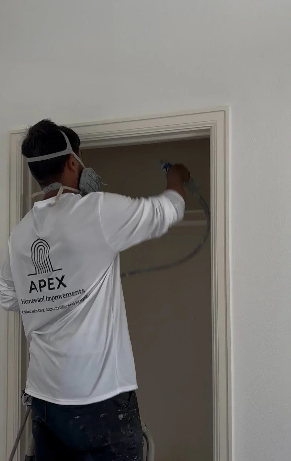 Painter applying paint to interior doorway trim and frame with brush