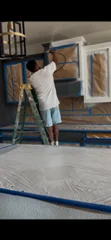 Painter applying ceiling paint with roller and extension pole indoors