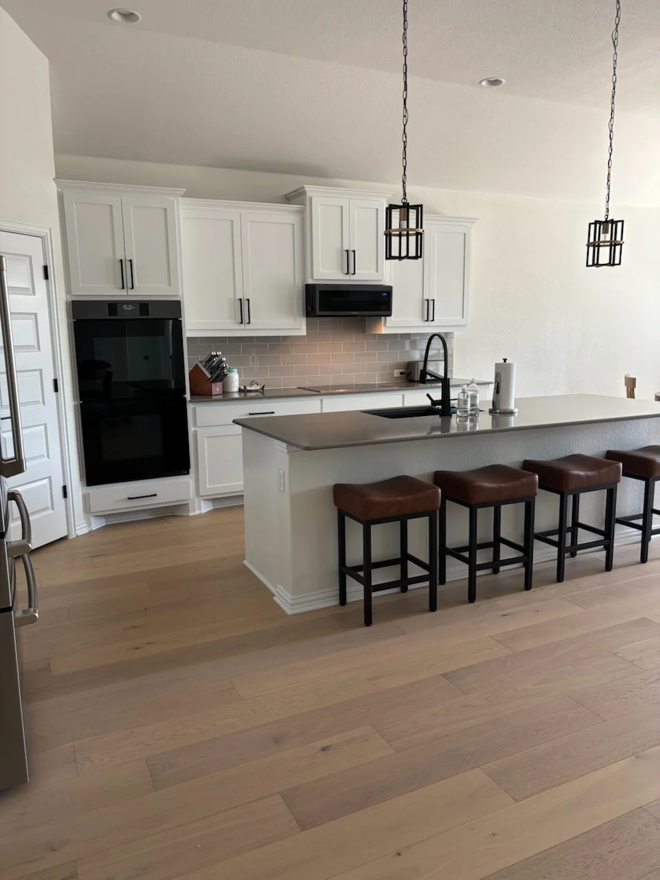 White painted kitchen cabinets, neutral ceiling, and walls in contemporary kitchen with island and bar seating