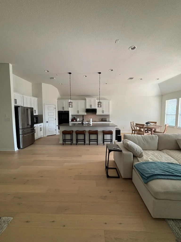 Freshly painted open-concept kitchen and living room with white walls, painted ceiling, and neutral trim