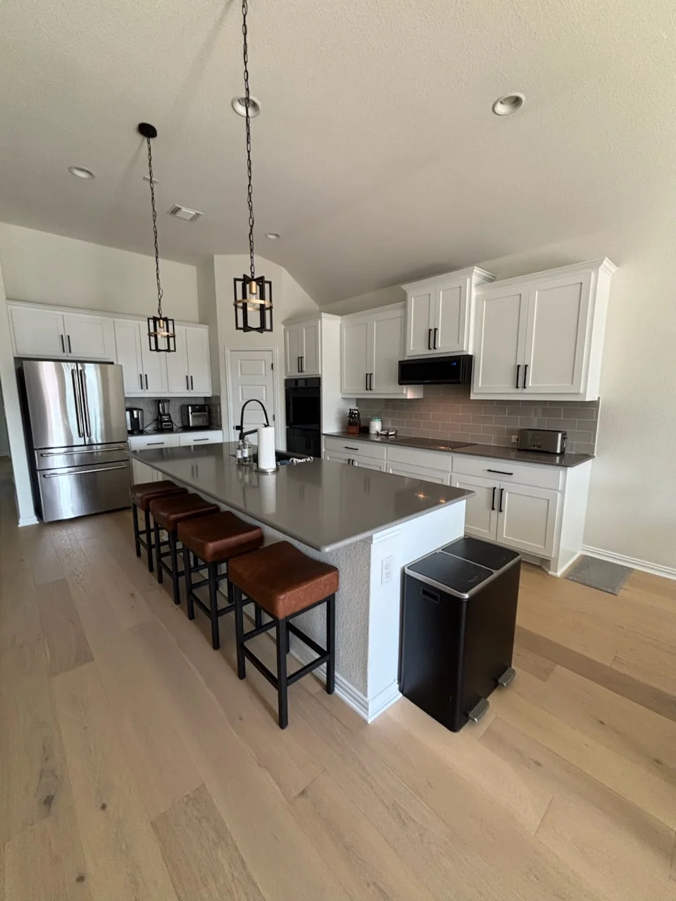 White painted kitchen cabinets, ceiling, and walls with gray countertops and black hardware